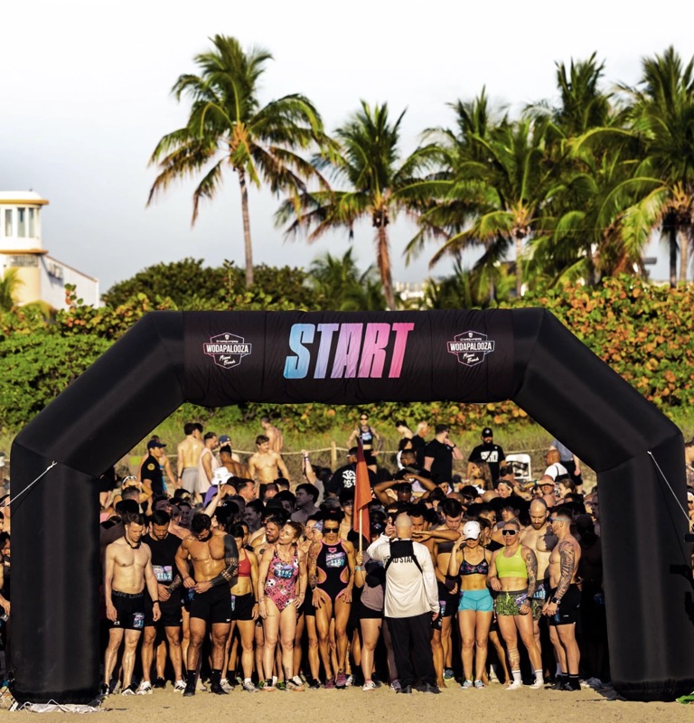 Athletes lined up at the start line beneath the Wodapalooza START arch on Miami Beach